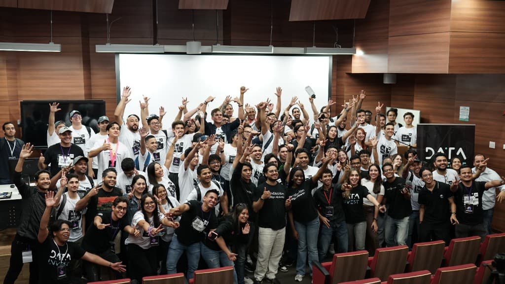 Foto grupal de la comunidad tech del Caribe con las manos en alto al final de un evento.